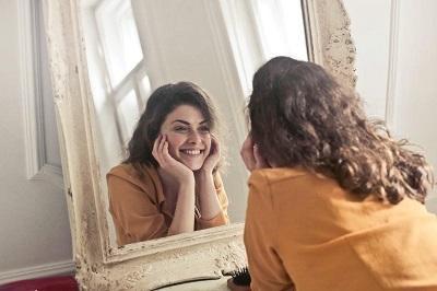 Woman staring into a mirror smiling