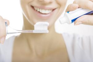 A woman puts toothpaste on her toothbrush