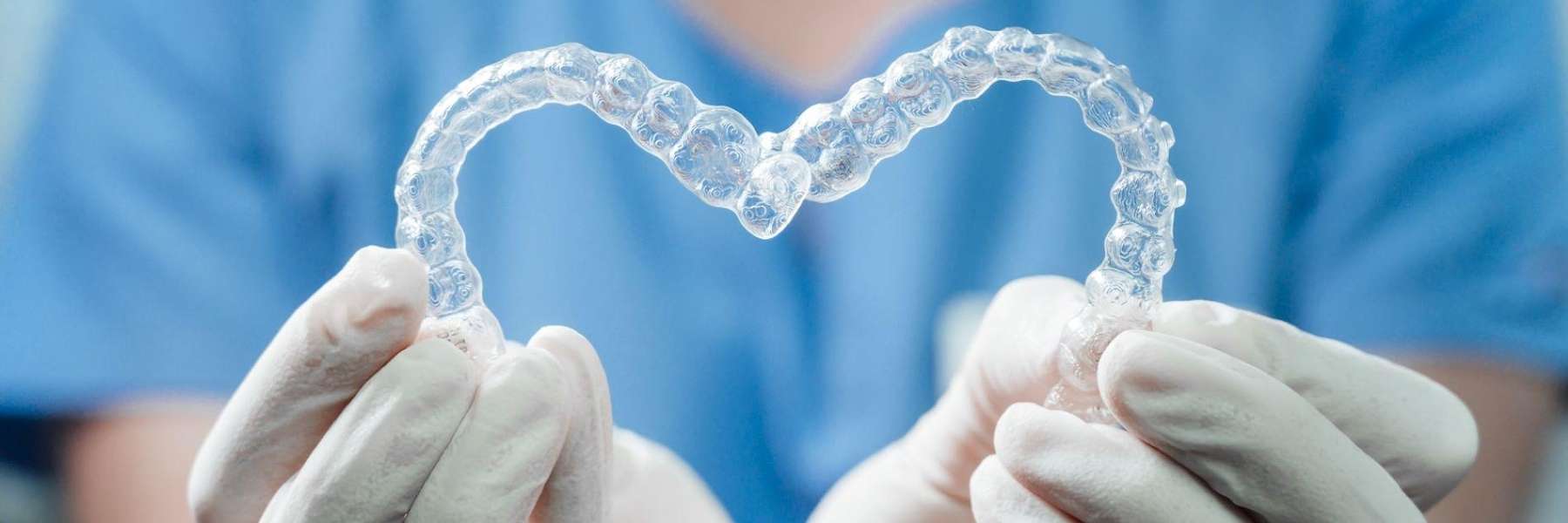 Dentist holding Invisalign aligners in a heart shape in Evansville