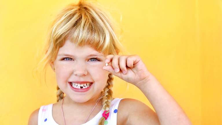 A young girl flexing her fallen tooth in Evansville IN